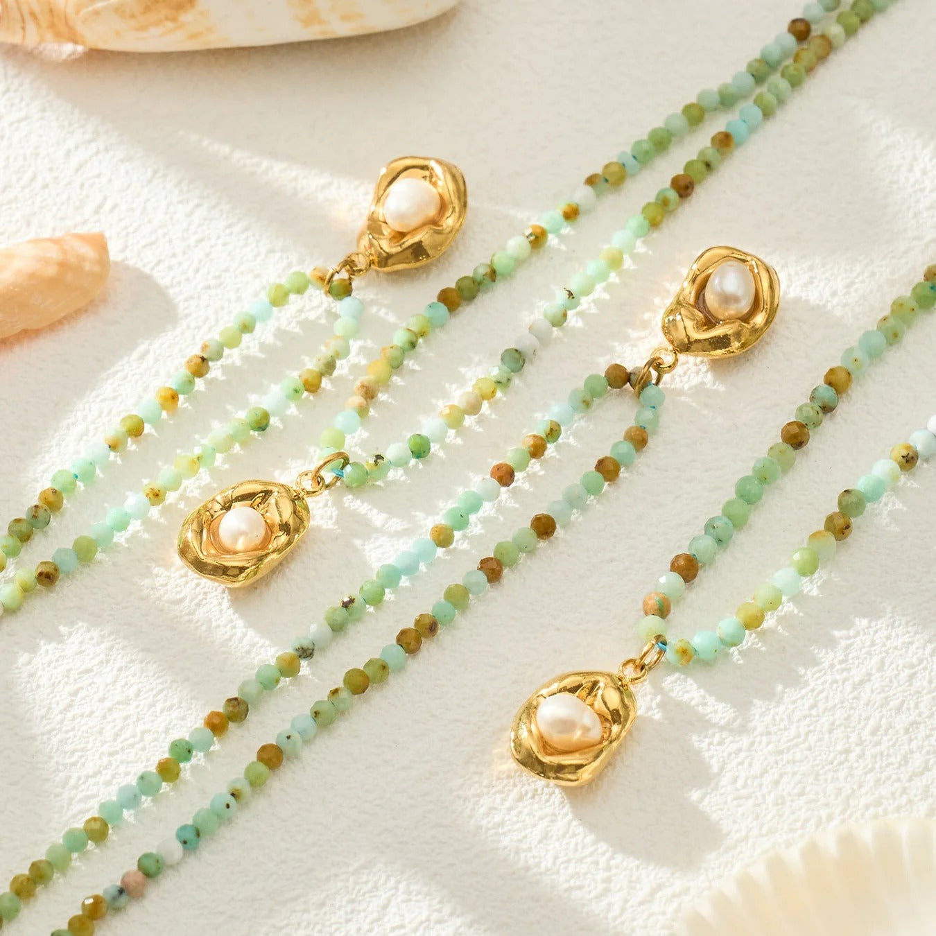 Mint green stone bead necklace with gold pearl pendant flat lay